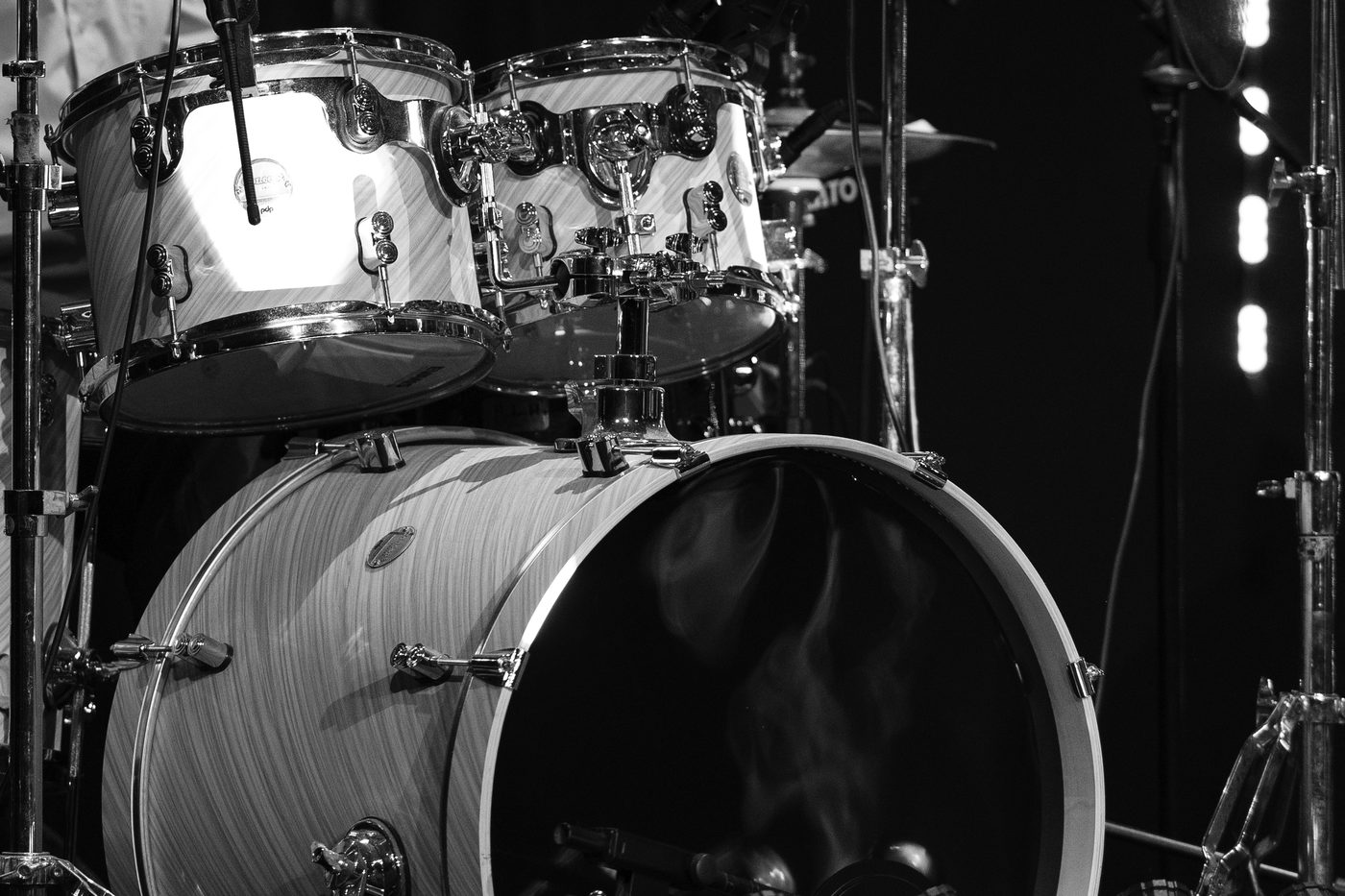 A drum kit lit on a dark stage between sets.